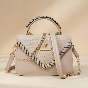 small, light-colored faux leather top-handle crossbody bag with a woven flap and chain details.