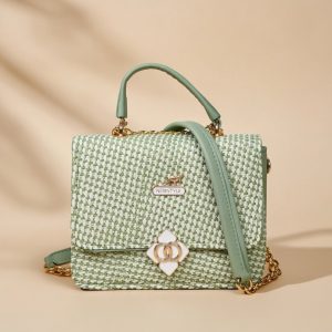 small green woven crossbody bag with a floral-shaped clasp.